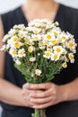 Woman wearing blck dress holding bunch of white Daisy flowers