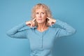 Woman wearing blue clothes plugging her ears wanting to stop loud noise. Royalty Free Stock Photo