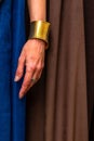 Woman wearing a blue dress stands in profile, proudly displaying a silver ring and a golden bracelet Royalty Free Stock Photo