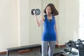 Woman wearing blue and gray sportswear while holding dumbbells. fitness slim young woman lifting weights in gym.