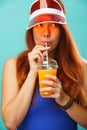 Woman wearing a blue swimsuit and hat drinks fruit juice from a cup Royalty Free Stock Photo