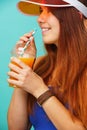Woman wearing a blue swimsuit and hat drinks fruit juice from a cup Royalty Free Stock Photo