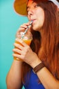 Woman wearing a blue swimsuit and hat drinks fruit juice from a cup Royalty Free Stock Photo