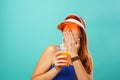 Woman wearing a blue swimsuit and hat drinks fruit juice from a cup Royalty Free Stock Photo