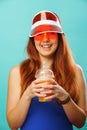 Woman wearing a blue swimsuit, hat and sunglasses drinks fruit juice from a cup Royalty Free Stock Photo