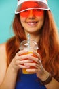 Woman wearing a blue swimsuit, hat and sunglasses drinks fruit juice from a cup Royalty Free Stock Photo