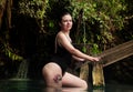 Woman wearing bodysuit with tattoo coming out of a river tropical amazon landscape Colombia