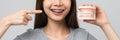 woman wearing braces showing pointing finger and holding tooth model on grey background. Royalty Free Stock Photo