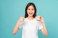 woman wearing braces showing thumbs up or like and holding tooth model on blue background Royalty Free Stock Photo