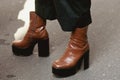 Woman wearing brown leather platform shoes and black leather skirt