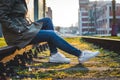 Woman wearing casual clothing and white sneakers sitting on rails