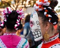 Woman wearing colorful skull mask and hair ribbons for Dia de Los Muertos/Day of the Dead