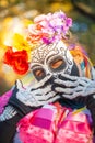 Woman wearing colorful skull mask and paper flowers for Dia de Los Muertos/Day of the Dead