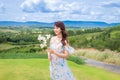 Woman wearing cute dress holding white flowers with beautiful scenery Royalty Free Stock Photo