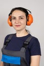 A woman wearing earmuffs and overalls on a white background. Clothing and items for builders, engineer