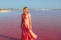 Woman wearing elegant summer dotted dress walking at bang of salty pink lake with crystals of salt Royalty Free Stock Photo