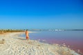 Woman wearing elegant summer dotted dress walking at bang of salty pink lake with crystals of salt. Extremely salty pink lake, Royalty Free Stock Photo
