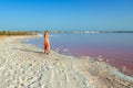 Woman wearing elegant summer dotted dress walking at bang of salty pink lake with crystals of salt. Extremely salty pink lake, Royalty Free Stock Photo