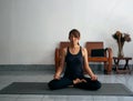 Woman wearing exercise suit ,sitting on yoga mat and closed her eyes,meditating,prepare for yoga  at home Royalty Free Stock Photo