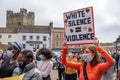 A woman wearing a face mask holds an anti-racism banner above her head with Richmond Castle in the background at a BLM protest in