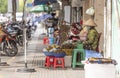 A woman wearing a face mask sits on a stool in front of a fruit stand Royalty Free Stock Photo