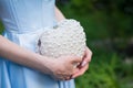 Woman wearing a formal blue satin dress holding a heart-shaped handbag with pearls - detail, close-up view. Royalty Free Stock Photo
