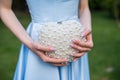 Woman wearing a formal blue satin dress holding a heart-shaped handbag with pearls - detail, close-up view. Royalty Free Stock Photo