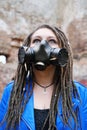 Woman wearing gas mask with spikes in blue jacket and black dress standing in ruined building is looking up Royalty Free Stock Photo