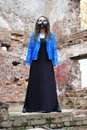 Woman wearing gas mask with spikes in blue jacket and black dress standing in ruined building Royalty Free Stock Photo