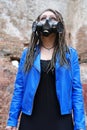 Woman wearing gas mask with spikes in blue jacket and black dress standing in ruined building Royalty Free Stock Photo