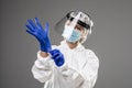 Woman wearing gloves with biohazard chemica protective suit isolated on gray background