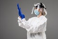 Woman wearing gloves with biohazard chemica protective suit isolated on gray background