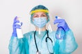 Woman wearing gloves, biohazard protective suit, face shield and mask with hand sanitizer bottle and disinfection gel. corona