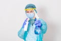 Woman wearing gloves, biohazard protective suit, face shield and mask with hand sanitizer bottle and disinfection gel. corona