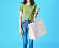 Woman wearing green shirts holding shopping bags in the blue background. Royalty Free Stock Photo