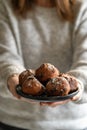 Close-up of a plate of oliebollen (Dutch doughnuts) with icing sugar held by a woman