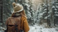 A woman wearing a hat and backpack in a snowy forest, hiking and winter travelling by foot, adventure concept. Royalty Free Stock Photo