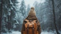 A woman wearing a hat and backpack in a snowy forest, hiking and winter travelling by foot, adventure concept. Royalty Free Stock Photo