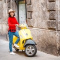 woman wearing hat standing near yellow scooter in Italy