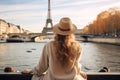 A woman wearing a hat stands, looking at the iconic Eiffel Tower in Paris, Young traveler woman rear view sitting on the quay of