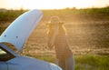 Woman wearing hat stranded in field with broken down car Royalty Free Stock Photo