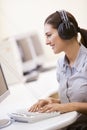 Woman wearing headphones in computer room typing Royalty Free Stock Photo