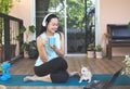 Woman wearing headphones, holding coffee cup, sitting  on yoga mat in balcony  with computer laptop Chihuahua dog, smiling and Royalty Free Stock Photo