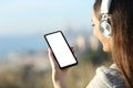 Woman wearing headphones showing blank phone screen