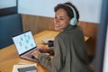 A woman wearing headphones is using a laptop computer at a table Royalty Free Stock Photo