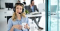 Woman wearing headset and holding coffee cup talking with customer during online phone call at helpdesk service office. Royalty Free Stock Photo