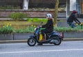 Woman wearing a helmet while riding a motorcycle. Woman driving scooter in downtown Vancouver