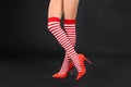 Woman wearing high heeled red shoes and festive socks against black background, closeup. Christmas celebration Royalty Free Stock Photo