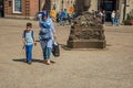 Woman wearing hijab headscarf and child walking in Amsterdam square.