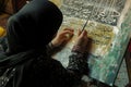 A woman wearing a hijab is seen writing on a canvas with focused concentration, A calligrapher painting Quranic verses, AI